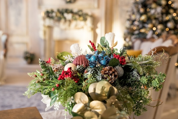 Living room.Christmas tree, contemporary fireplace , loft interior design apartment. table composition, vase made of fir tree with artificial snow, balls, bows, beads against the festive interior