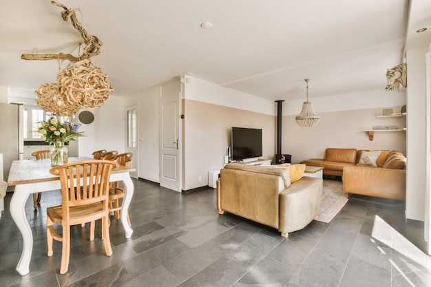 a living room and dining area in a house with stone flooring white walls and wooden furniture on the right side