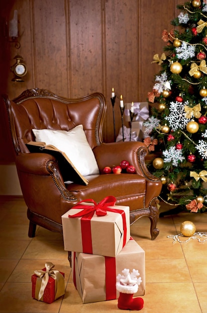 The living room in the house is decorated for Christmas Christmas tree decorated for the holiday and a lot of gifts next to it Retro armchair in the house