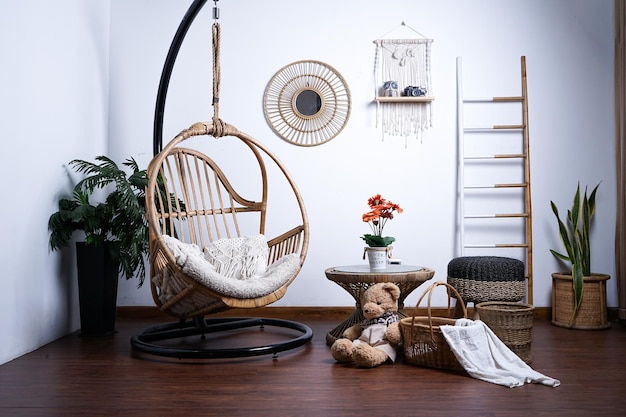 Living room interior with hanging rattan chair with bohemian decoration and elegant accessories.