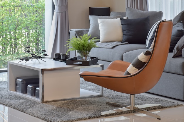 Living room with plant in vase and black pattern pillows on modern leather chair