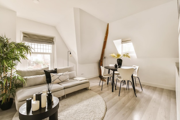 a living room with white walls and wood flooring in the center of the room there is a couch coffee table chair