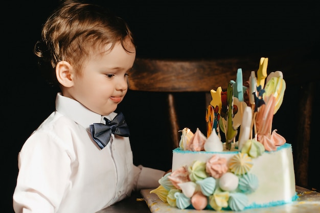 Llittle boy next to a cake for his birthday