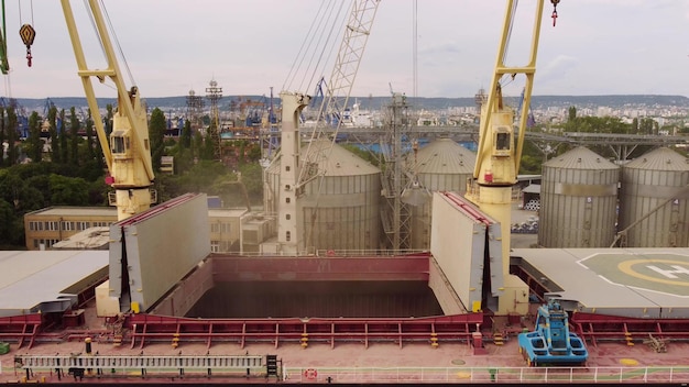 Loading grain into sea cargo vessel in seaport from silos of grain storage Aerial view