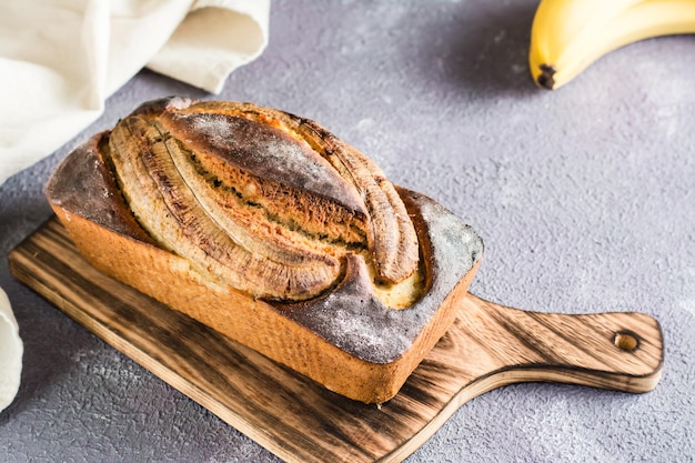 A loaf of baked banana bread on a cutting board on the table Social media trendy