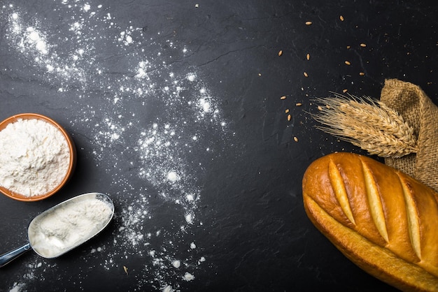 Loaf of bread and wheat flour on slate