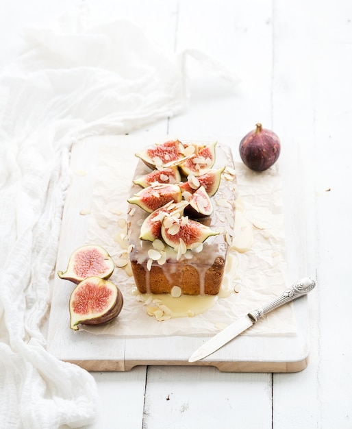 Loaf cake with figs, almond and white chocolate on wooden serving board over grunge table, selective focus.