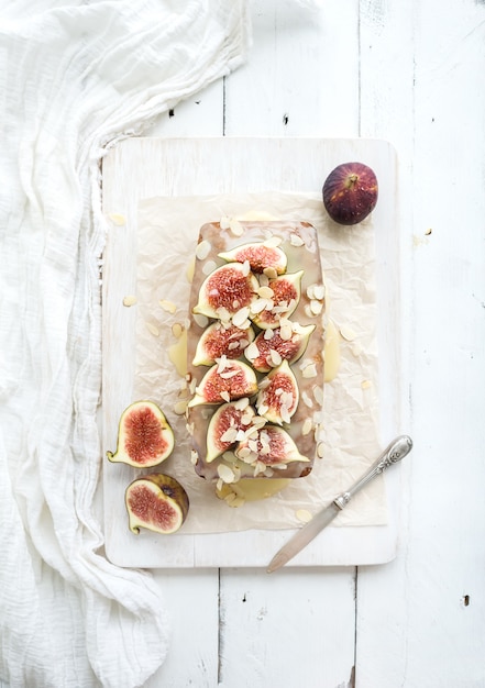 Loaf cake with figs, almond and white chocolate on wooden serving board