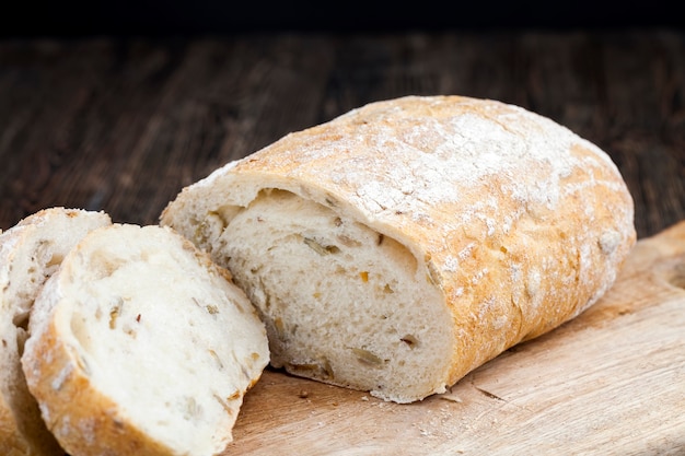 A loaf of fresh wheat bread on the table during cooking, soft fresh bread with pumpkin seeds and flax seeds