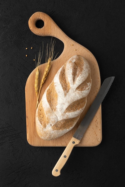 A loaf of gluten free bread on a wooden board on a black background