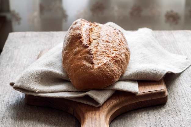 Loaf of whole wheat bread wooden board on kitchen table