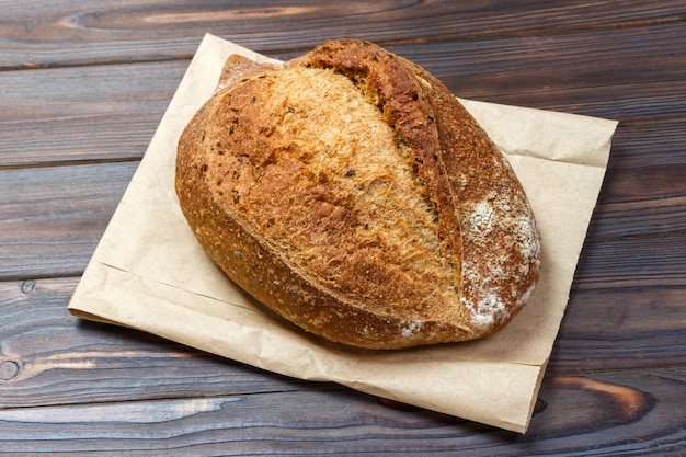 Loafs of fresh bread on wood table with paper bag. Top view