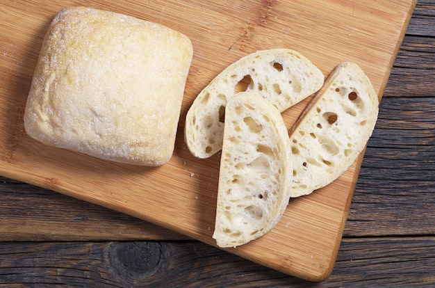 Loaves and slice of italian bread ciabatta on cutting board