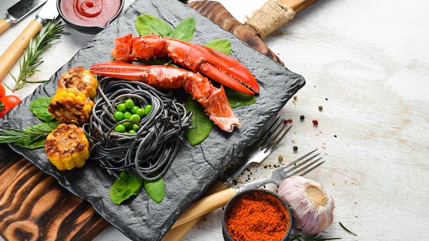 Lobster claw with black pasta and vegetables on the black stone plate Seafood Top view Free space for your text