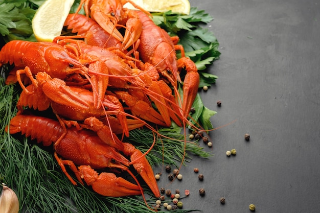 Lobsters with lemon lime green dill garlic and dry pepper on black background top view