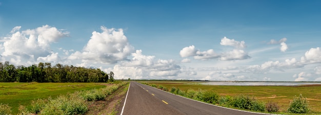 Local pavement road with grassland in rural scene on blue sky background