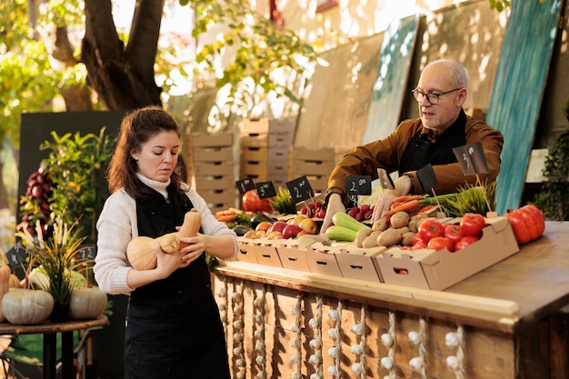 Photo local stand vendors starting the day with fresh natural produce, working at marketplace stall to sell healthy products. young woman putting fruits and vegetables on farmers market.