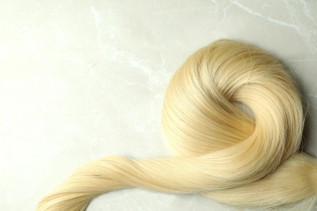 A lock of blond female hair on light background