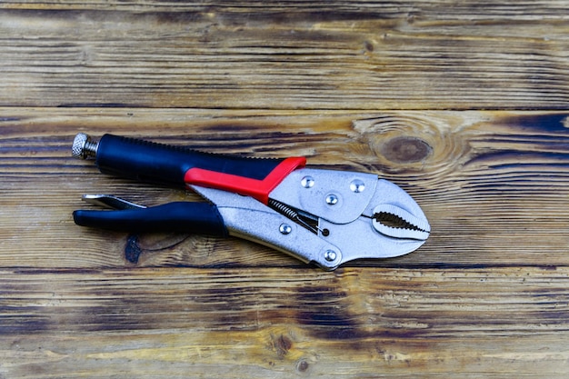 Locking pliers with red handles on a wooden background Top view