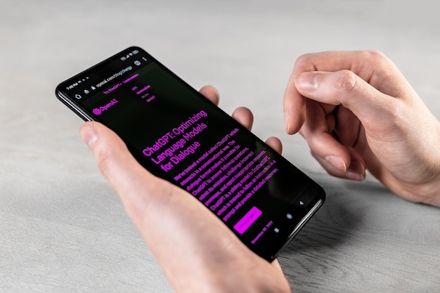 Lodz Poland March 01 2023 Hands with phone screen Open AI homepage website Using Chat GPT online bot service chatbot on smartphone display at desk