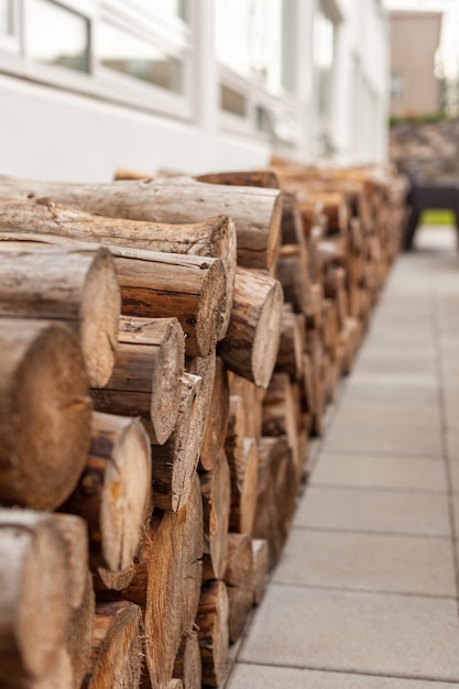 Logs woodpile near modern building house wall. Selective focus