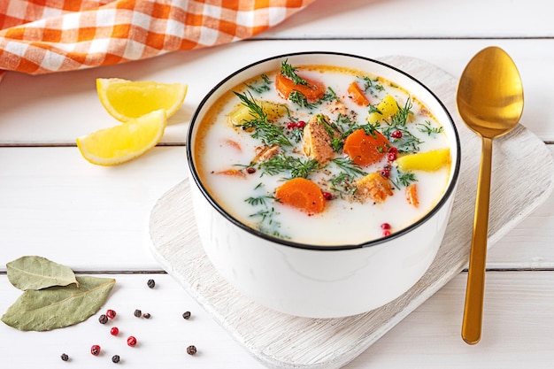 Lohikeitto Finnish traditional creamy salmon soup served in a white bowl White wooden tabletop