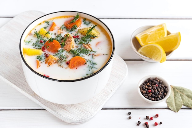 Lohikeitto Finnish traditional creamy salmon soup served in a white bowl White wooden tabletop