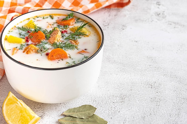 Lohikeitto Finnish traditional creamy salmon soup in a white bowl Light grey background copyspace