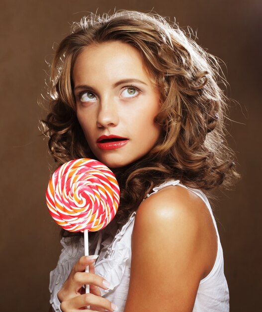 Lollipop in hand. Beautiful curly girl with  candy.