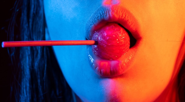 Lollipop in the mouth closeup beautiful girl mouth with lolli pop glossy red woman lips with tongue ...