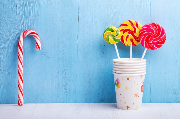 Lollipops in cups with candy canes on blue wooden wall