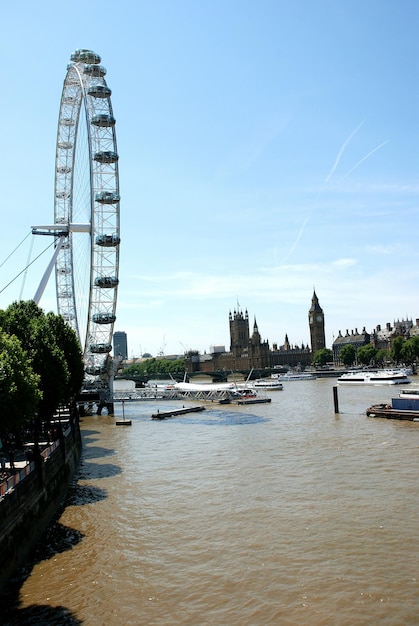 Photo london eye by river thames against sky