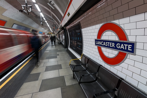 London Underground sign with moving train and people at Lancaster Gate station