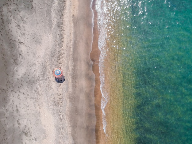 A lone beach umbrella on the sand beach, flat aerial view for background