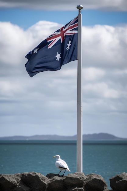 A lone bird stands on a flag pole with the ocean in the background.