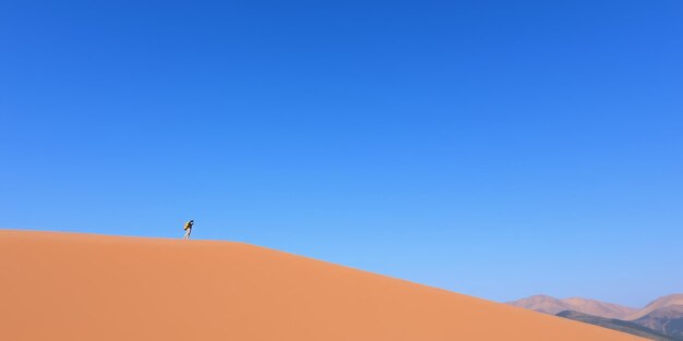 Photo a lone hiker walks across a vast desert dune