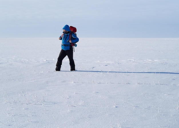 Lonely backpacker walking throw snow desert