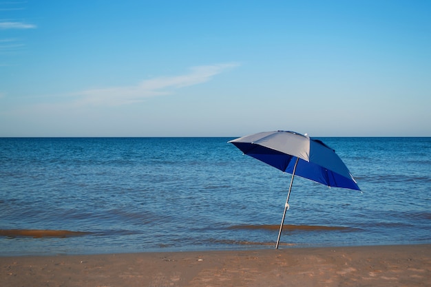 Lonely beach umbrella on the seashore on a sunny day against the backdrop of the sea.