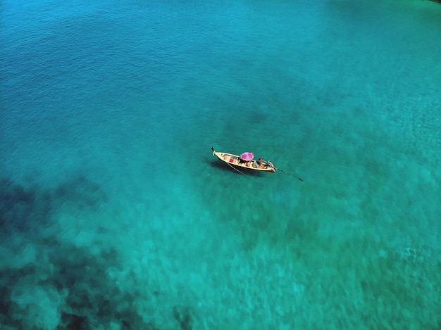 A lonely boat is floating peacefully in the middle of a vast blue ocean, aerial view