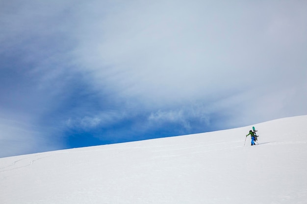 Lonely freerider traveler climbs the mountain against the background of the blue sky