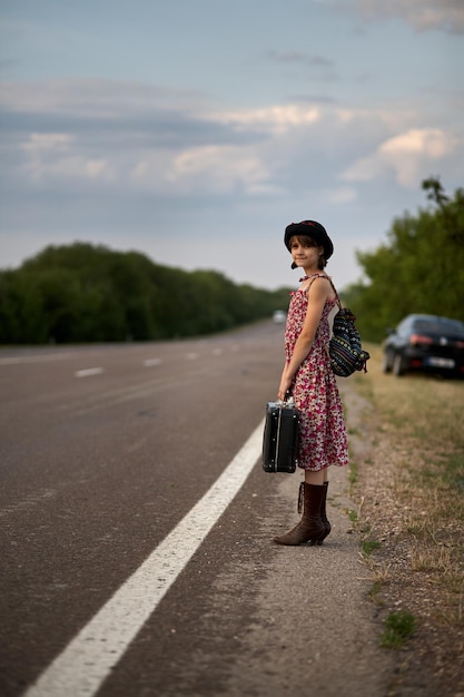 Lonely girl with suitcase standing about road