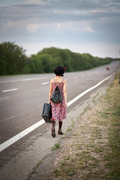 Lonely girl with suitcase standing about road