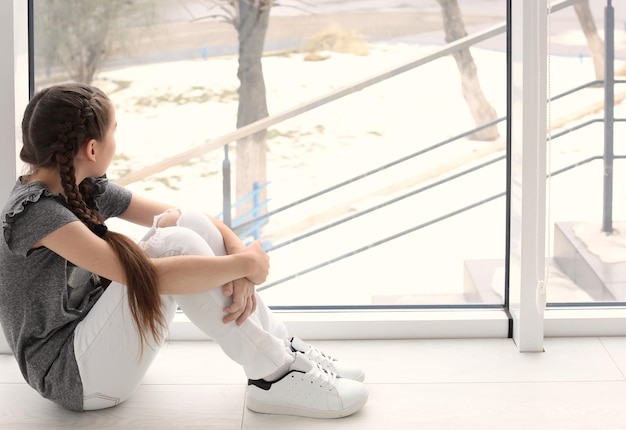 Lonely little girl near window indoors Child autism