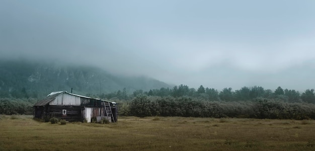 A lonely rural simple poor house near the hills under a thick morning fog near the forest a house on