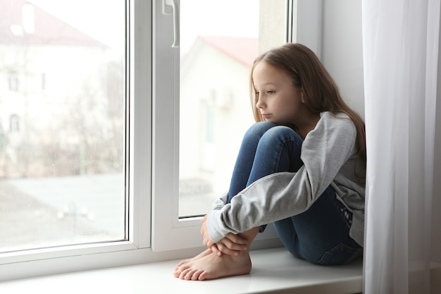 Lonely sad girl at home saddened alarmed child alone at home