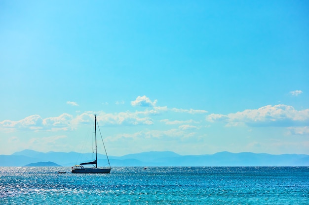 Lonely sail yacht in the sea and blue sky with clouds