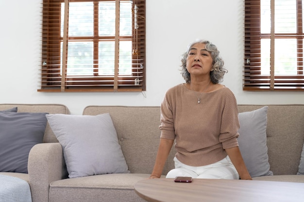 A lonely senior woman is waiting and thinking old memories of her family that will visit her againdepressed elderly people with loneliness and depression sitting alonemissingnostalgiaremembrance