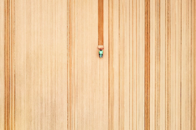 Lonely tractor on agricultural field with rows of plowed soil Agricultural fields prepared for planting crops topdown view Industrial agriculture concept Drone photography