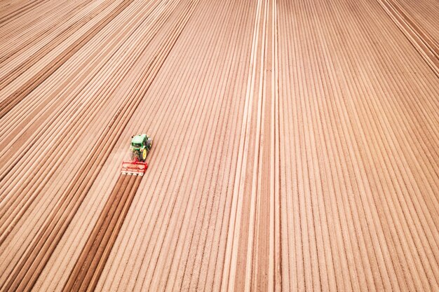 Lonely tractor on agricultural field with rows of plowed soil