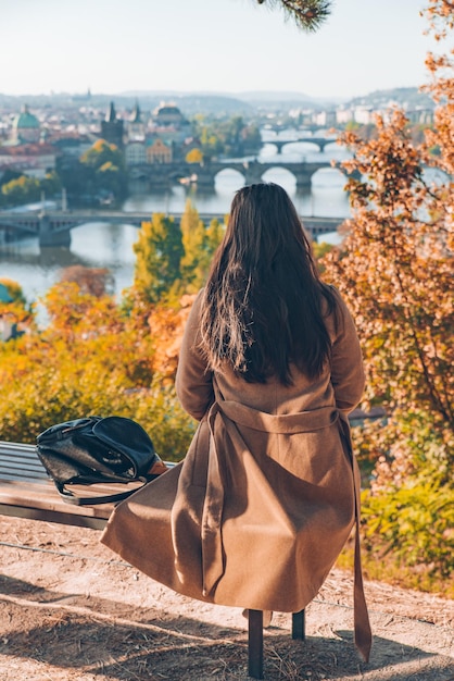 Lonely woman sitting at bench with beautiful view of autumn european city